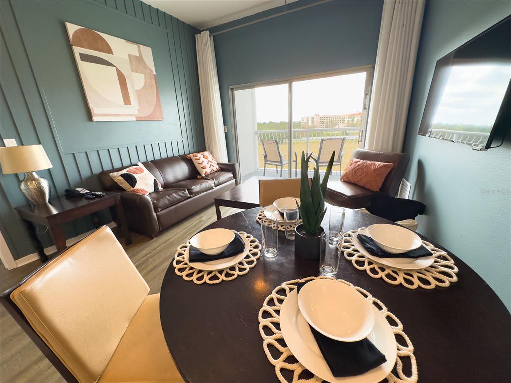 A dining area with a round table and a living room with a leather sofa — 225 CELEBRATION PLACE UNIT # 527, KISSIMMEE, FL
