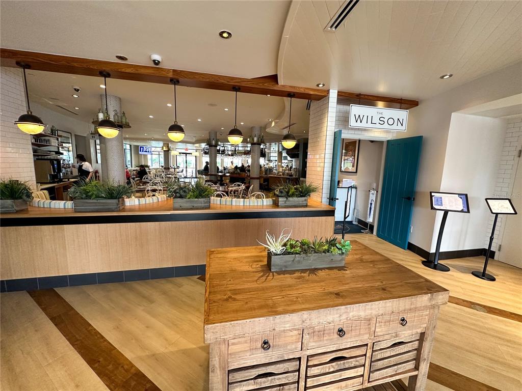 A restaurant interior features a wooden host stand, pendant lighting, and a blue door — 225 CELEBRATION PLACE UNIT # 527, KISSIMMEE, FL