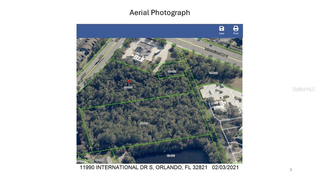 This aerial photograph shows a wooded lot outlined in green near a road and pond — 11990 INTERNATIONAL DRIVE, ORLANDO, FL