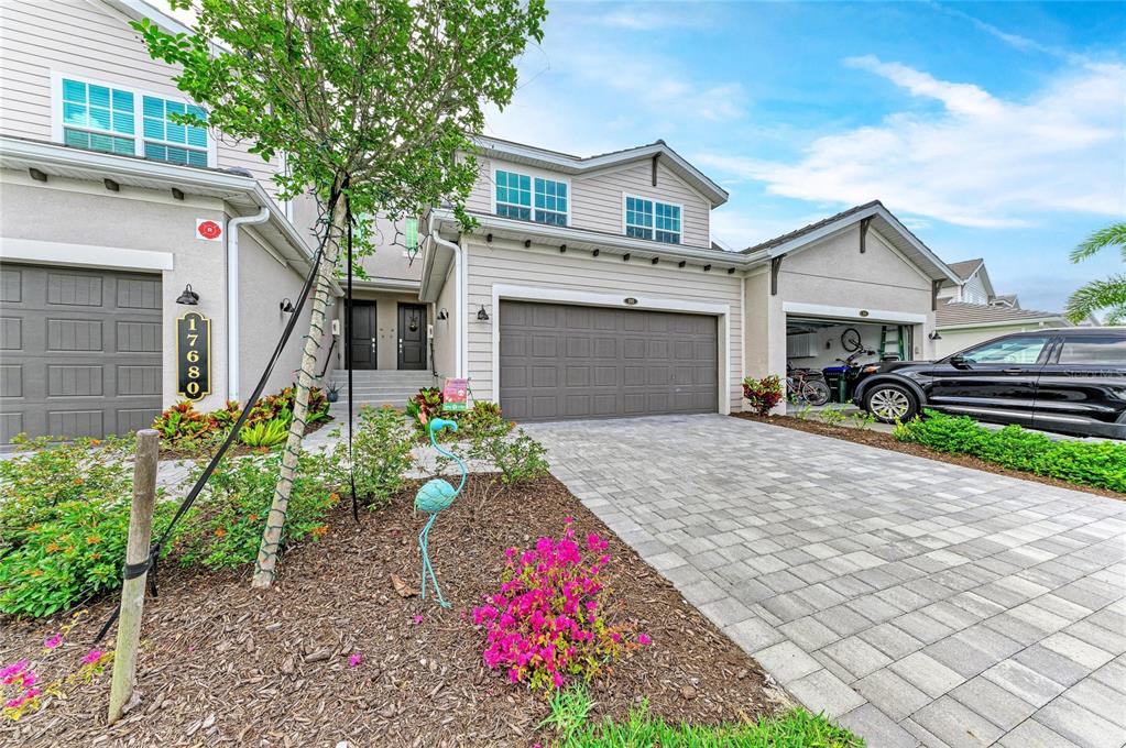 A two-story suburban home features a paved driveway, a two-car garage, and a landscaped yard — 17680 BORACAY COURT UNIT 202, VENICE, FL