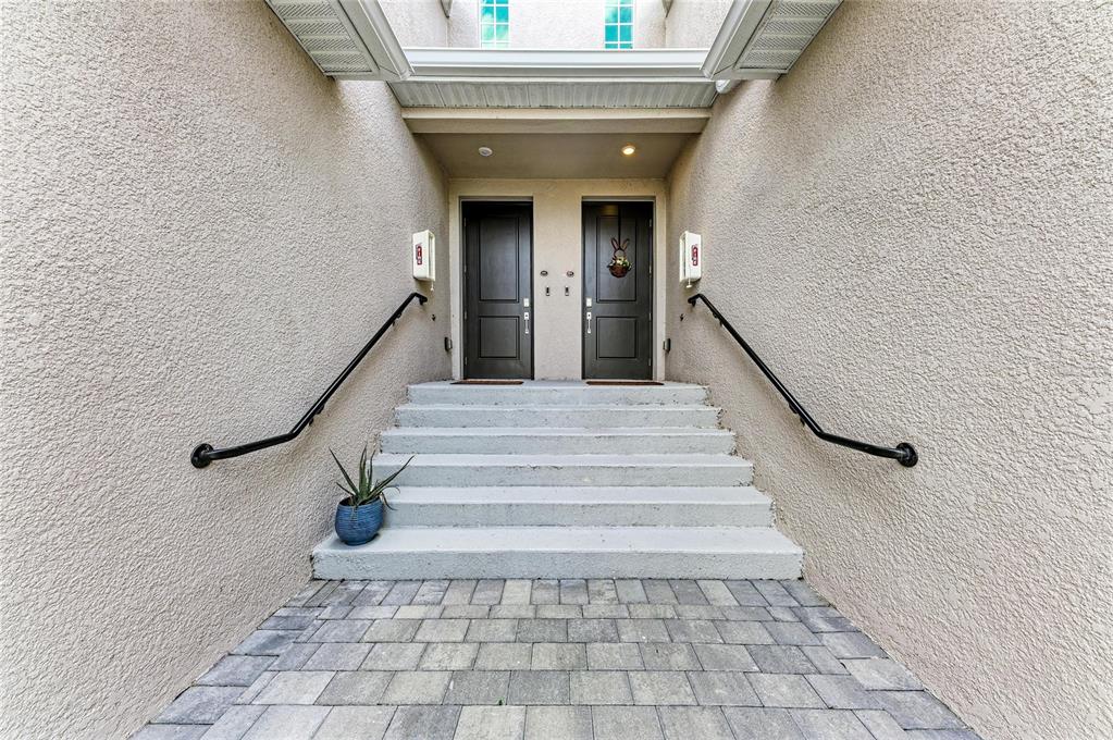 A set of concrete stairs leads to two dark brown front doors between stucco walls — 17680 BORACAY COURT UNIT 202, VENICE, FL