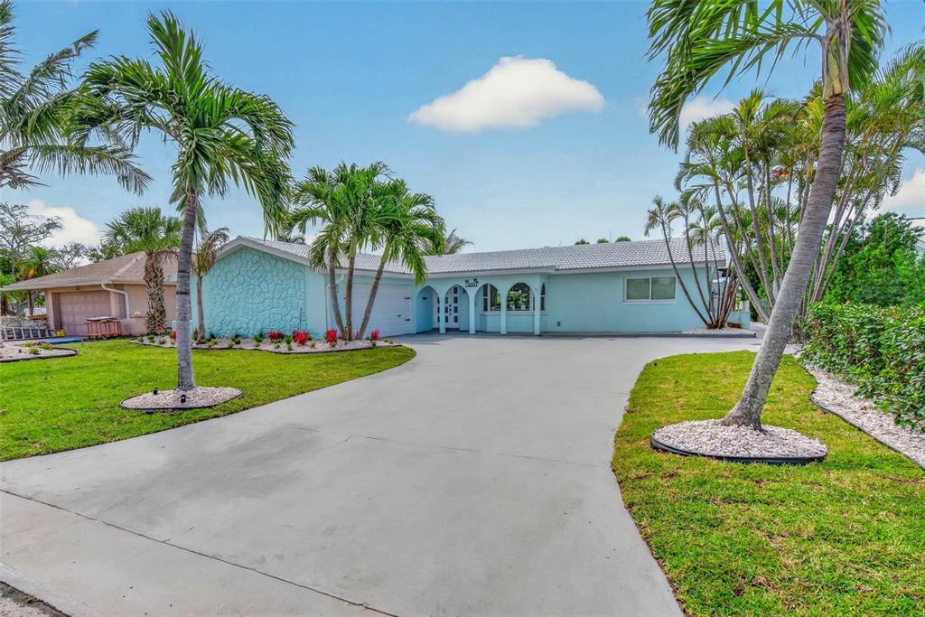 A light blue single-story house features a concrete driveway, palm trees, and a tiled roof — 650 64TH AVENUE, ST PETE BEACH, FL
