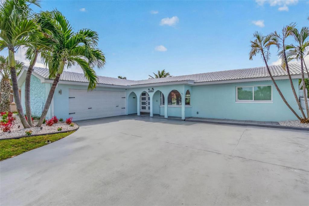 A light blue, single-story house with a tiled roof, arched entryway, and a concrete driveway — 650 64TH AVENUE, ST PETE BEACH, FL