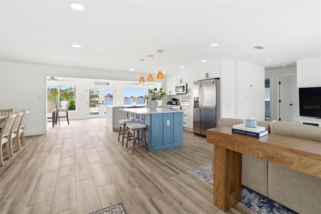 An open-concept kitchen features a blue island, white cabinetry, and wood-look tile flooring — 650 64TH AVENUE, ST PETE BEACH, FL