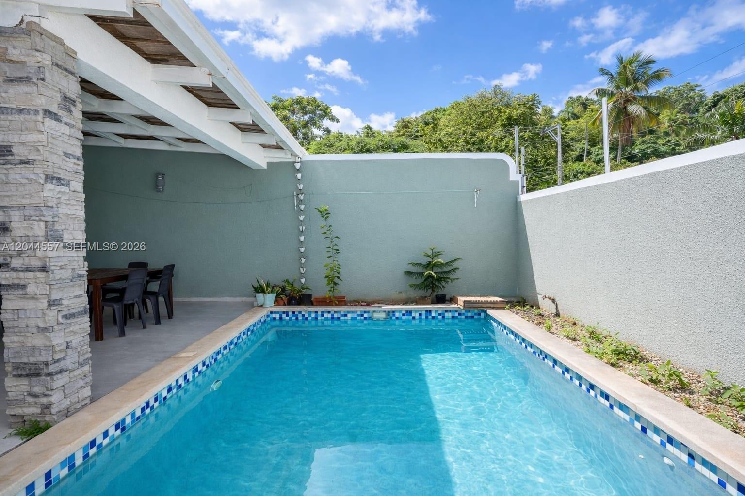 A rectangular swimming pool sits adjacent to a covered patio with a dining set — FL