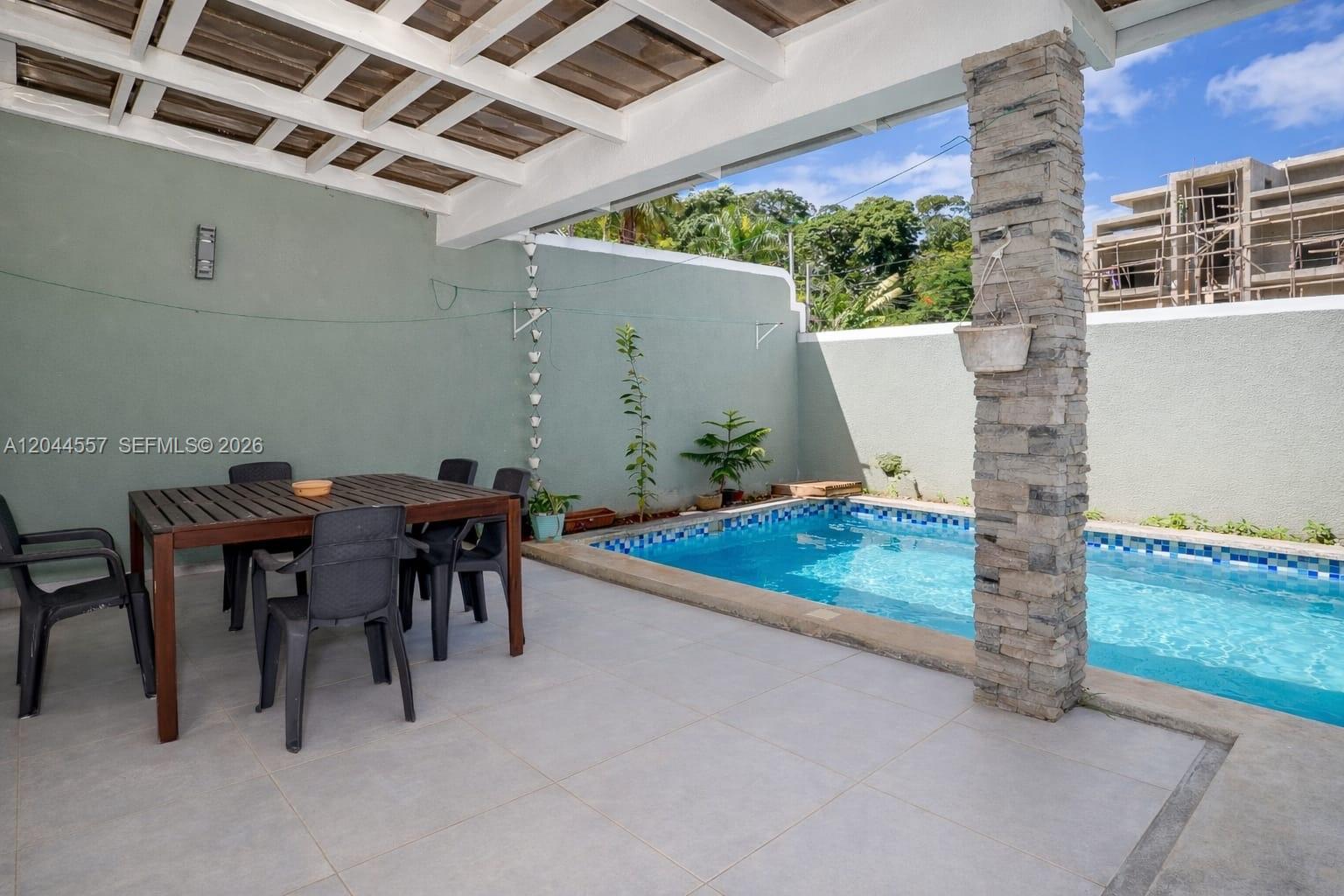 A covered patio features a dining table, chairs, and a small swimming pool — FL