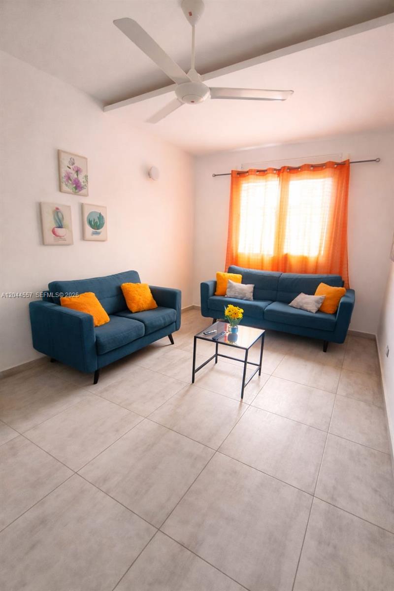 A living room features two blue sofas, a glass coffee table, and orange curtains — FL