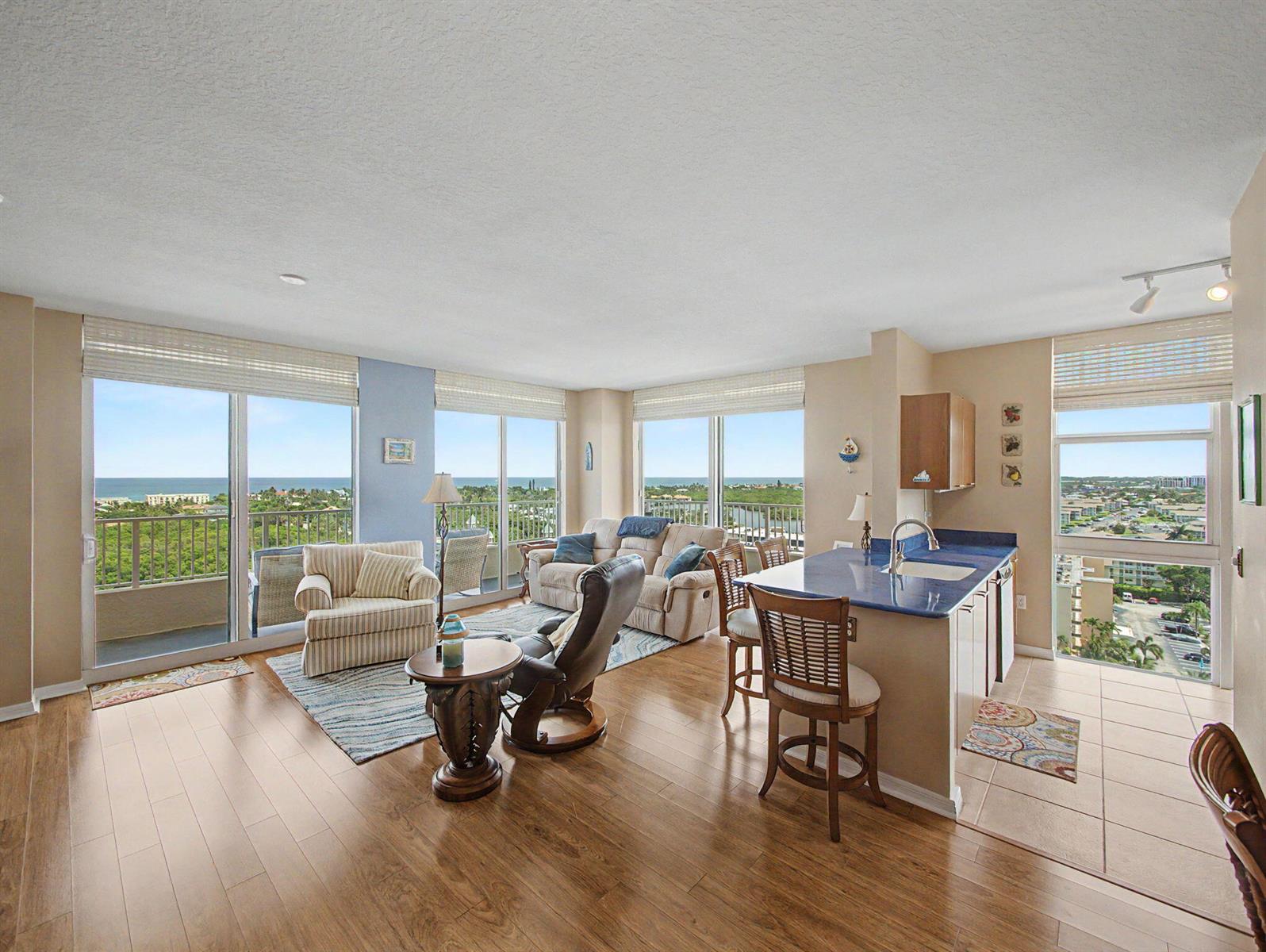 An open-concept living area with wood floors, a kitchen island, and floor-to-ceiling windows overlooking water — 625 Casa Loma Boulevard # 1402, Boynton Beach FL 33435, BOYNTON BEACH, FL