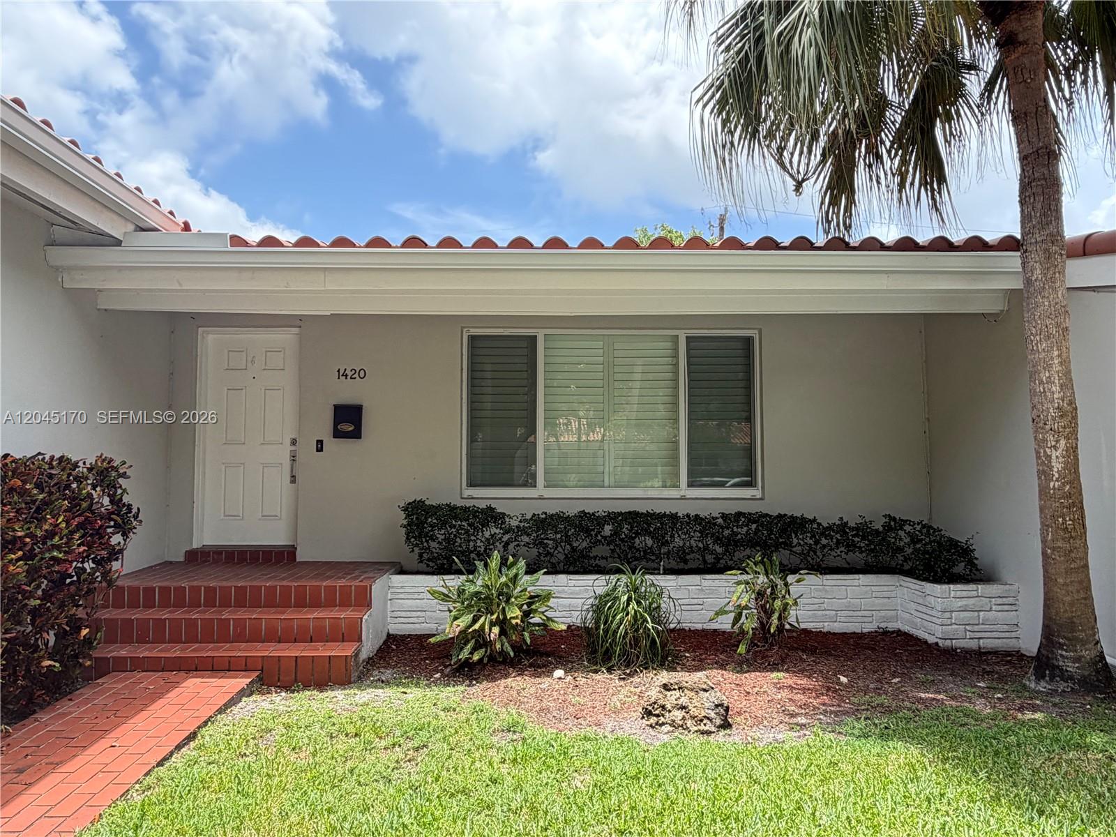 The exterior of a single-story house features a white facade, red tile roof, and brick steps — 1420 Baracoa Ave, Coral Gables FL 33146, CORAL GABLES, FL
