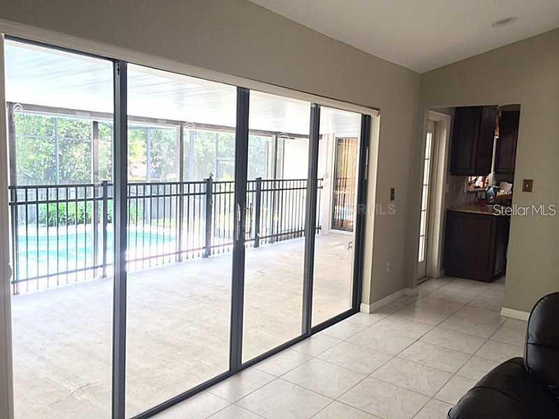 A room with tile flooring features a large sliding glass door overlooking a screened pool patio — 1114 SEAFARER LANE, WINTER SPRINGS, FL