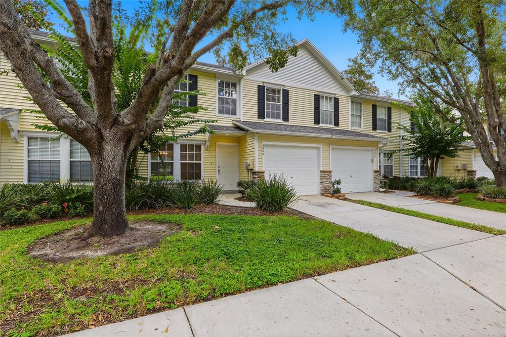 A two-story yellow townhouse with a two-car garage and a front yard with trees — 3006 AMBER OAK DRIVE, VALRICO, FL