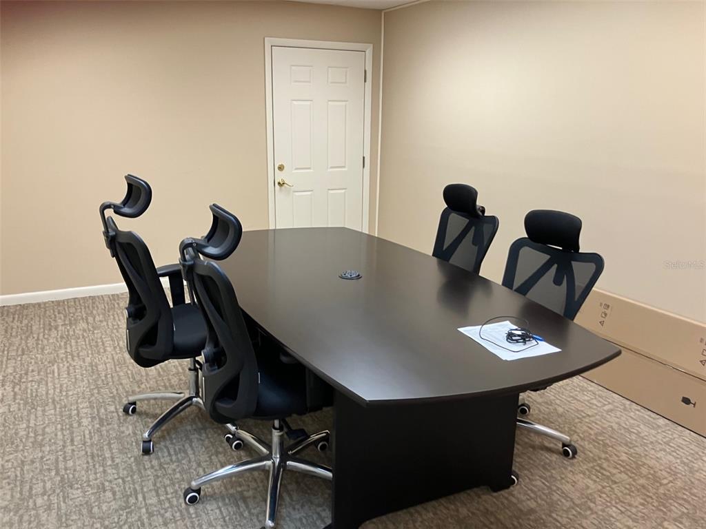 A conference room features a dark wood table, four black office chairs, and beige carpet — 4233 W EL PRADO BOULEVARD, TAMPA, FL