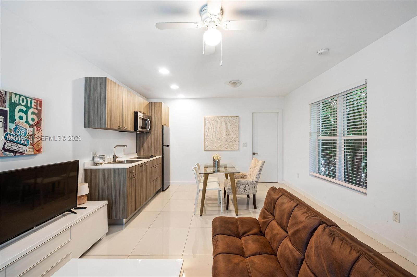 A small kitchen and dining area with a brown sofa in a living room — 1419 West Ave # 201, Miami Beach FL 33139, MIAMI BEACH, FL