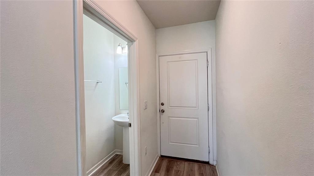 A hallway features a white door and an open doorway leading to a small bathroom — 1340 MIRABELLA CIRCLE, DAVENPORT, FL