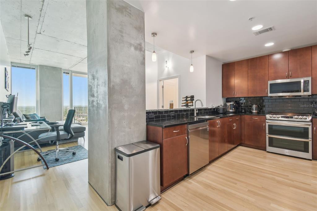 A kitchen with wood cabinets and black countertops sits adjacent to a living area — 777 N ASHLEY DRIVE UNIT 3009, TAMPA, FL