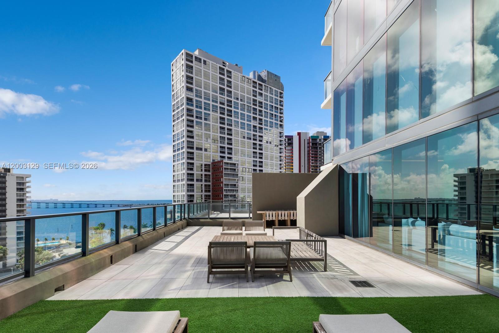 A spacious outdoor balcony features patio furniture, artificial turf, and views of the bay — 1451 Brickell Ave # 903, Miami FL 33131, MIAMI, FL
