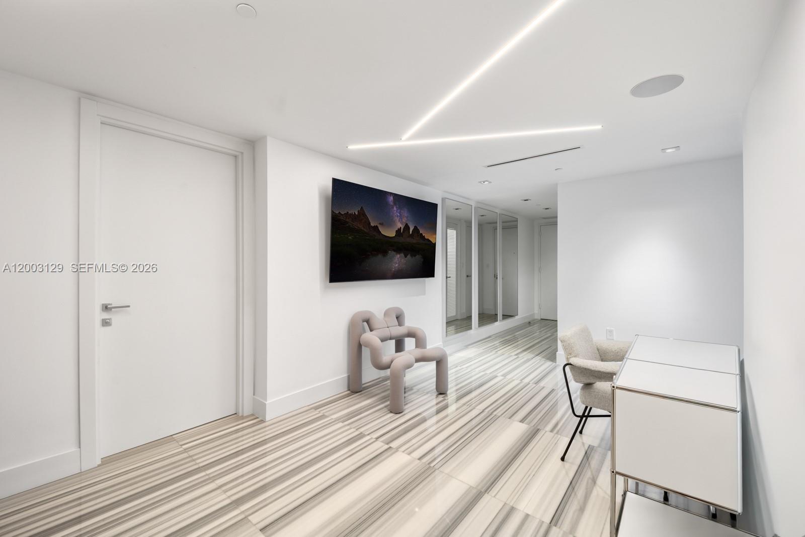 A modern room features white walls, striped tile flooring, a wall-mounted television, and minimalist furniture — 1451 Brickell Ave # 903, Miami FL 33131, MIAMI, FL