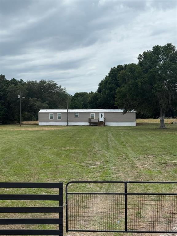 A single-story manufactured home sits in the middle of a large, grassy fenced lot — 21 RIDGE ROAD, FROSTPROOF, FL