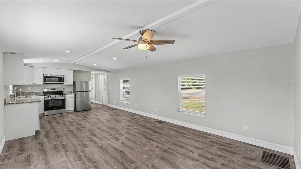 A kitchen and living area with light gray walls, wood-look flooring, and stainless steel appliances — 21 RIDGE ROAD, FROSTPROOF, FL
