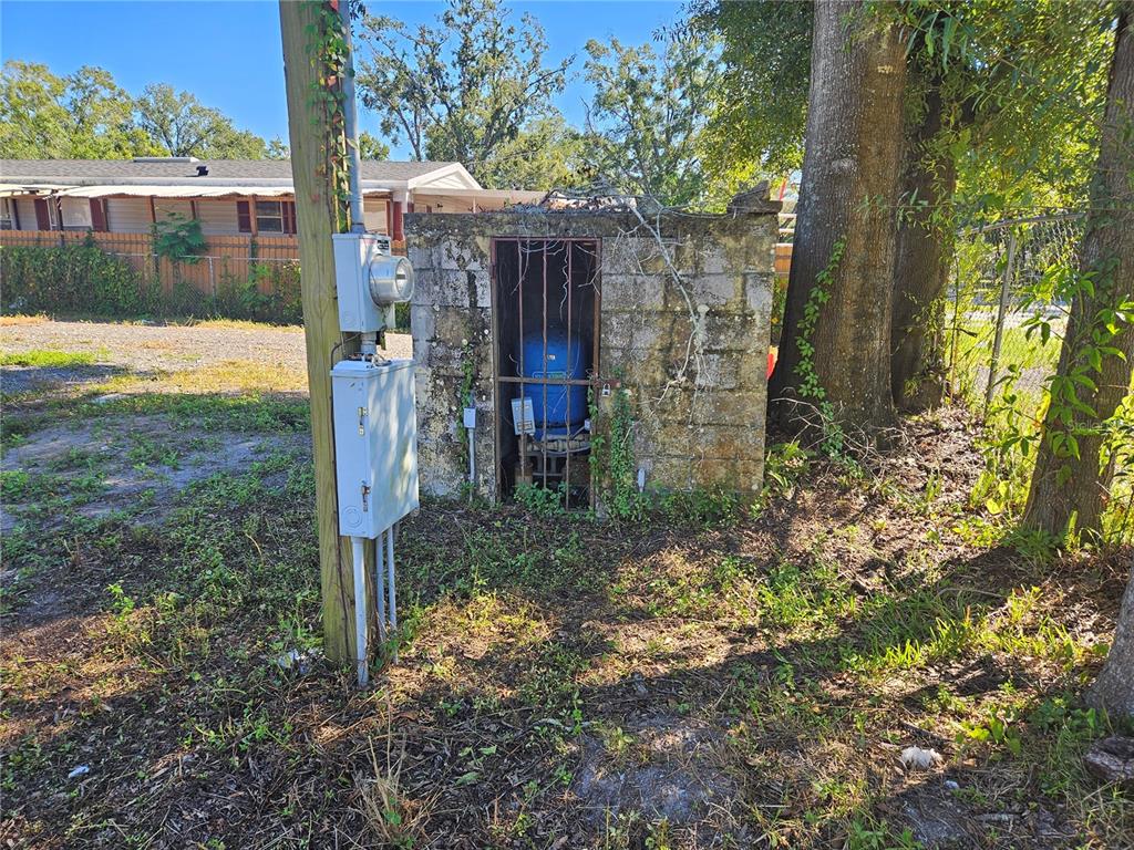 A utility shed with a blue pressure tank stands outdoors next to an electrical pole — 12321 CAMBRIDGE AVENUE, TAMPA, FL