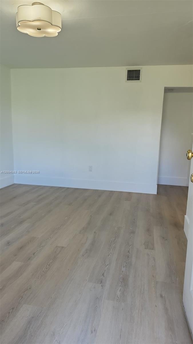 An empty room features light-colored wood-look flooring, white walls, and a decorative ceiling light fixture — 2651 NW 13th St # 41, Miami FL 33125, MIAMI, FL