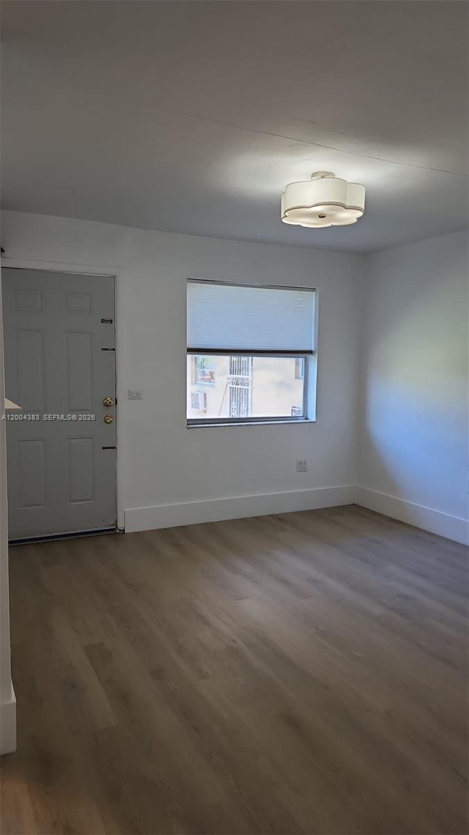 An empty room features light wood-look flooring, white walls, a gray door, and a window — 2651 NW 13th St # 41, Miami FL 33125, MIAMI, FL
