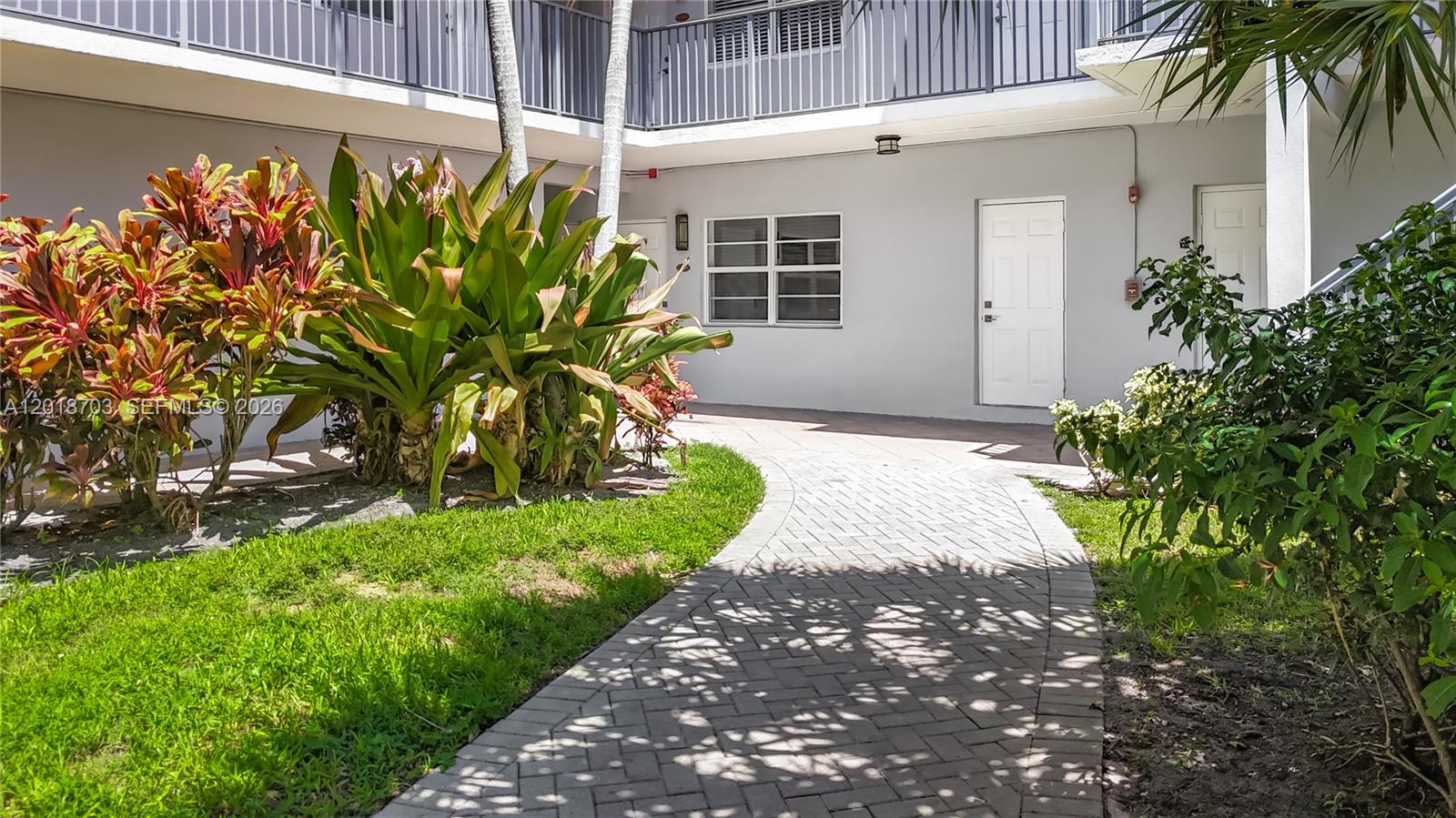 A paved walkway leads to white doors at the entrance of a multi-story apartment building — 2600 S Ocean Dr # S102, Hollywood FL 33019, HOLLYWOOD, FL