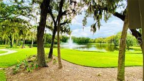 A view of a grassy lawn, trees, and a pond with a fountain — 5246 WEDGEWOOD LANE UNIT 60, SARASOTA, FL