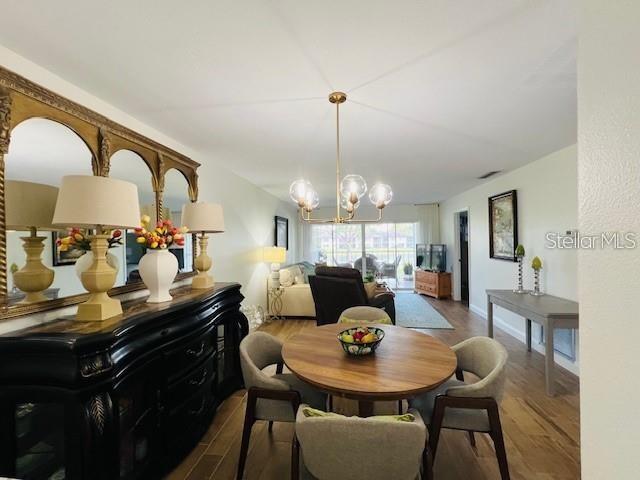 A dining area and living room with wood-look tile floors overlook a golf course balcony — 5246 WEDGEWOOD LANE UNIT 60, SARASOTA, FL