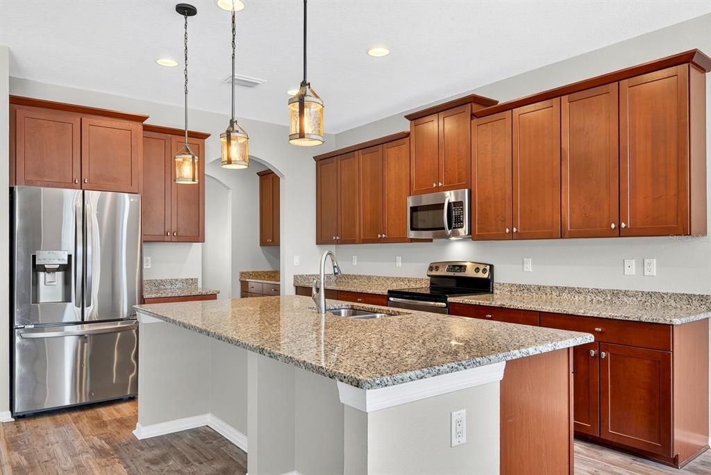 A kitchen features wood cabinets, granite countertops, stainless steel appliances, and a central island — 3938 90TH AVENUE E, PARRISH, FL