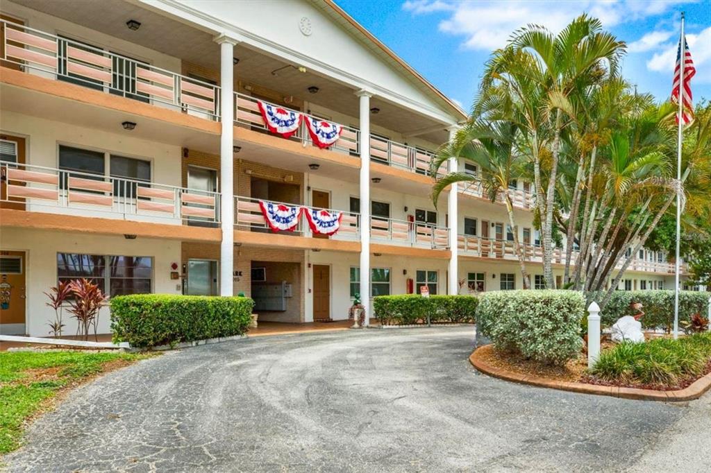 A three-story apartment building with exterior walkways, white columns, and a paved circular driveway — 6015 19TH STREET N UNIT 302, ST PETERSBURG, FL