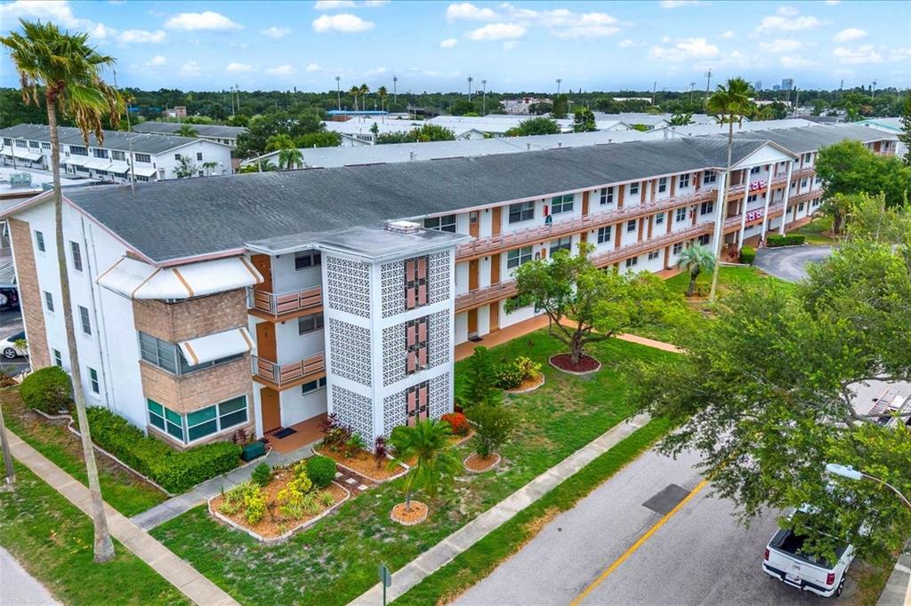 An outdoor walkway with a brown door numbered 302 overlooks trees and a pond — 6015 19TH STREET N UNIT 302, ST PETERSBURG, FL