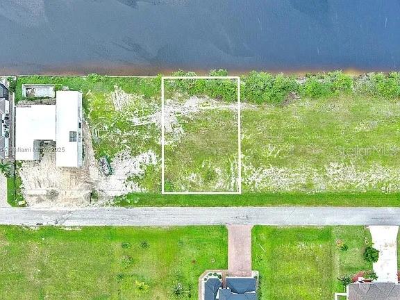 An aerial view shows a vacant rectangular lot bordering a body of water — 1228 NW 34TH AVENUE, CAPE CORAL, FL