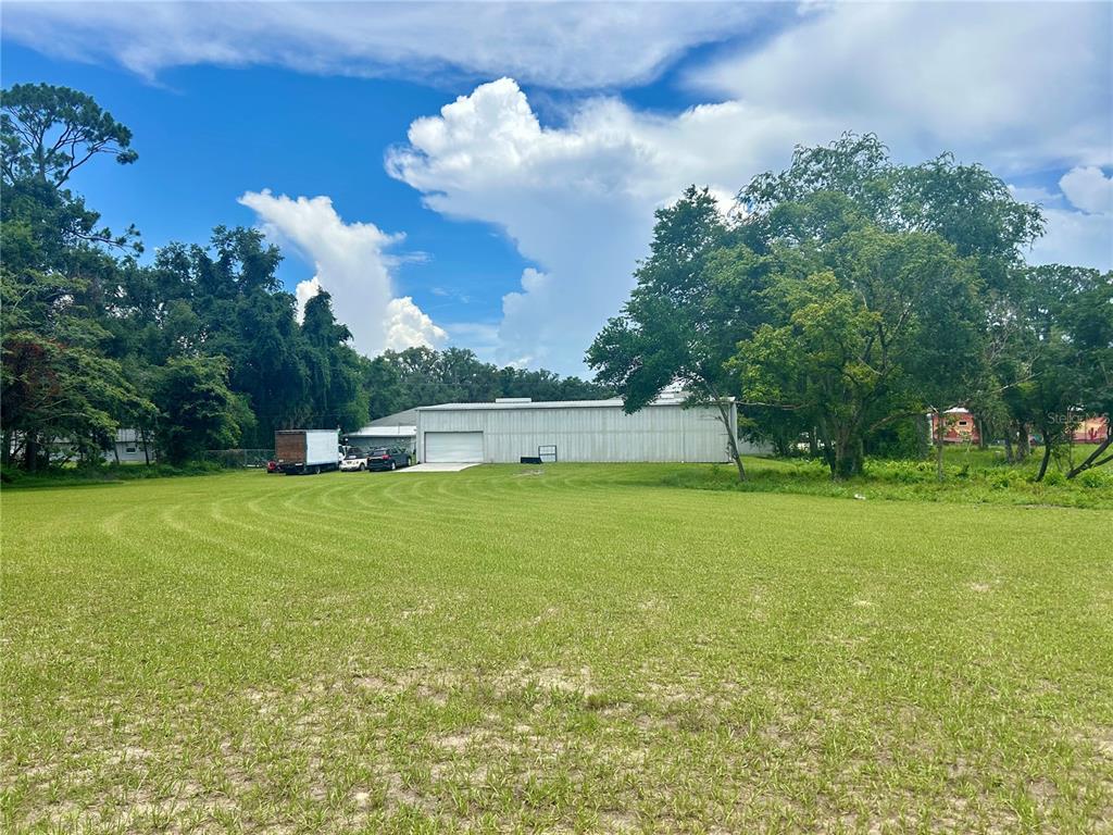 A large metal warehouse building sits at the back of a wide, grassy lot — 19808 N US HIGHWAY 441, HIGH SPRINGS, FL