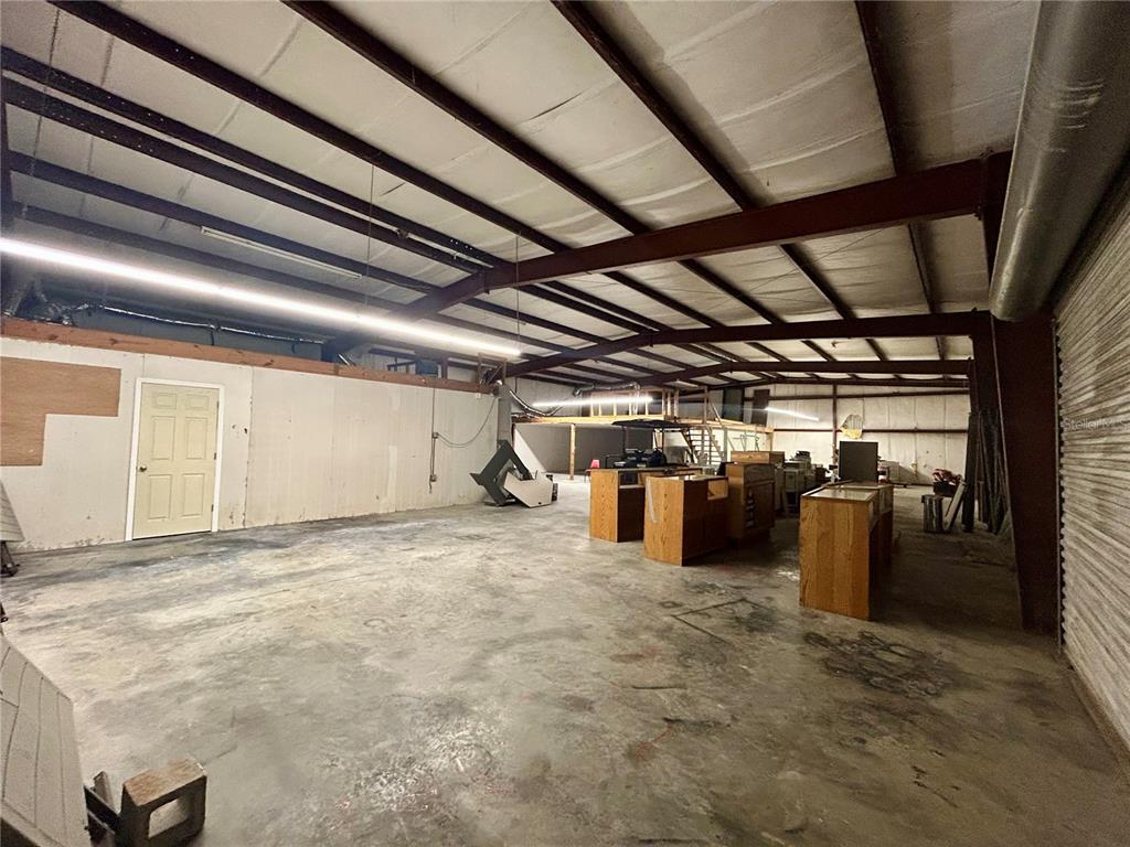 An industrial warehouse space features a concrete floor, exposed steel beams, and wooden display counters — 19808 N US HIGHWAY 441, HIGH SPRINGS, FL