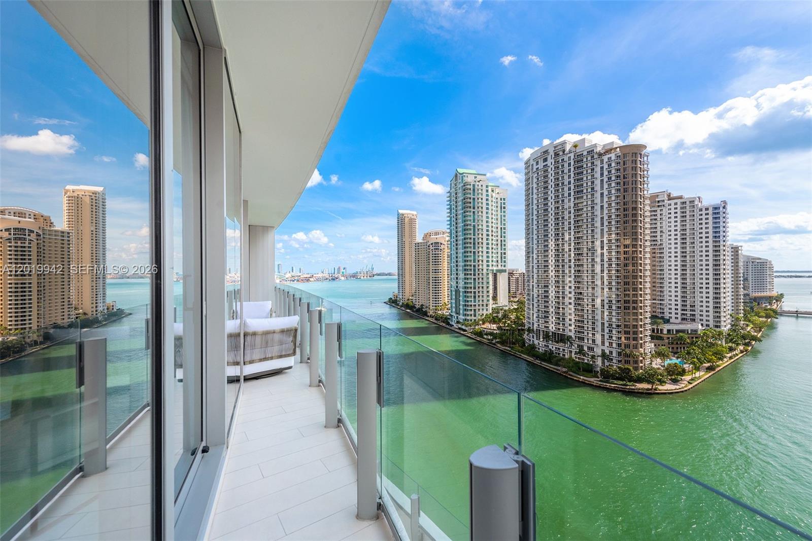 A high-rise balcony with glass railings overlooks a waterway and a city skyline — 300 Biscayne Blvd Way # 1605, Miami FL 33131, MIAMI, FL