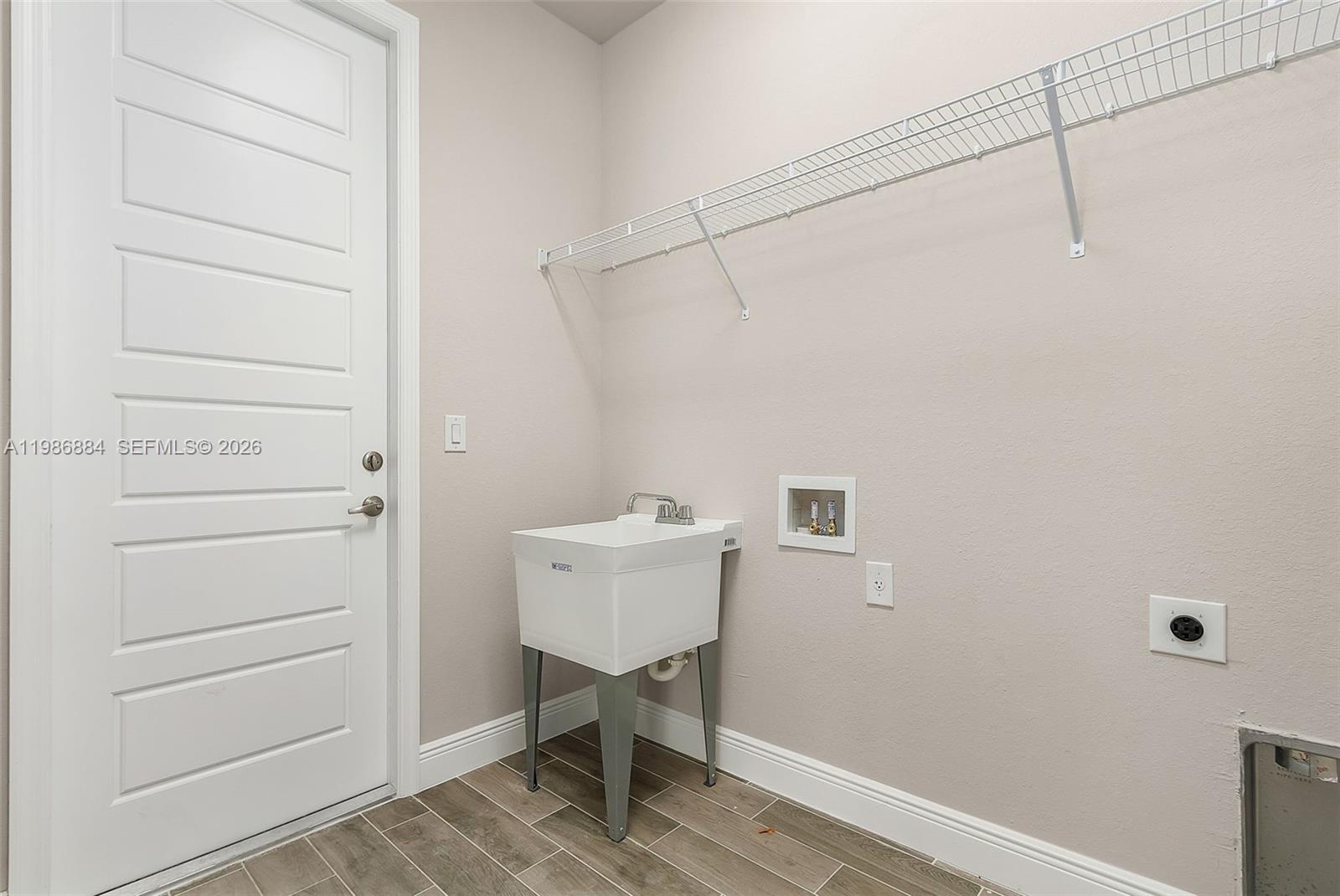A laundry room features a utility sink, a wire shelf, and washer-dryer hookups — 206 Jubilee Terr, La Belle FL 33935, LA BELLE, FL