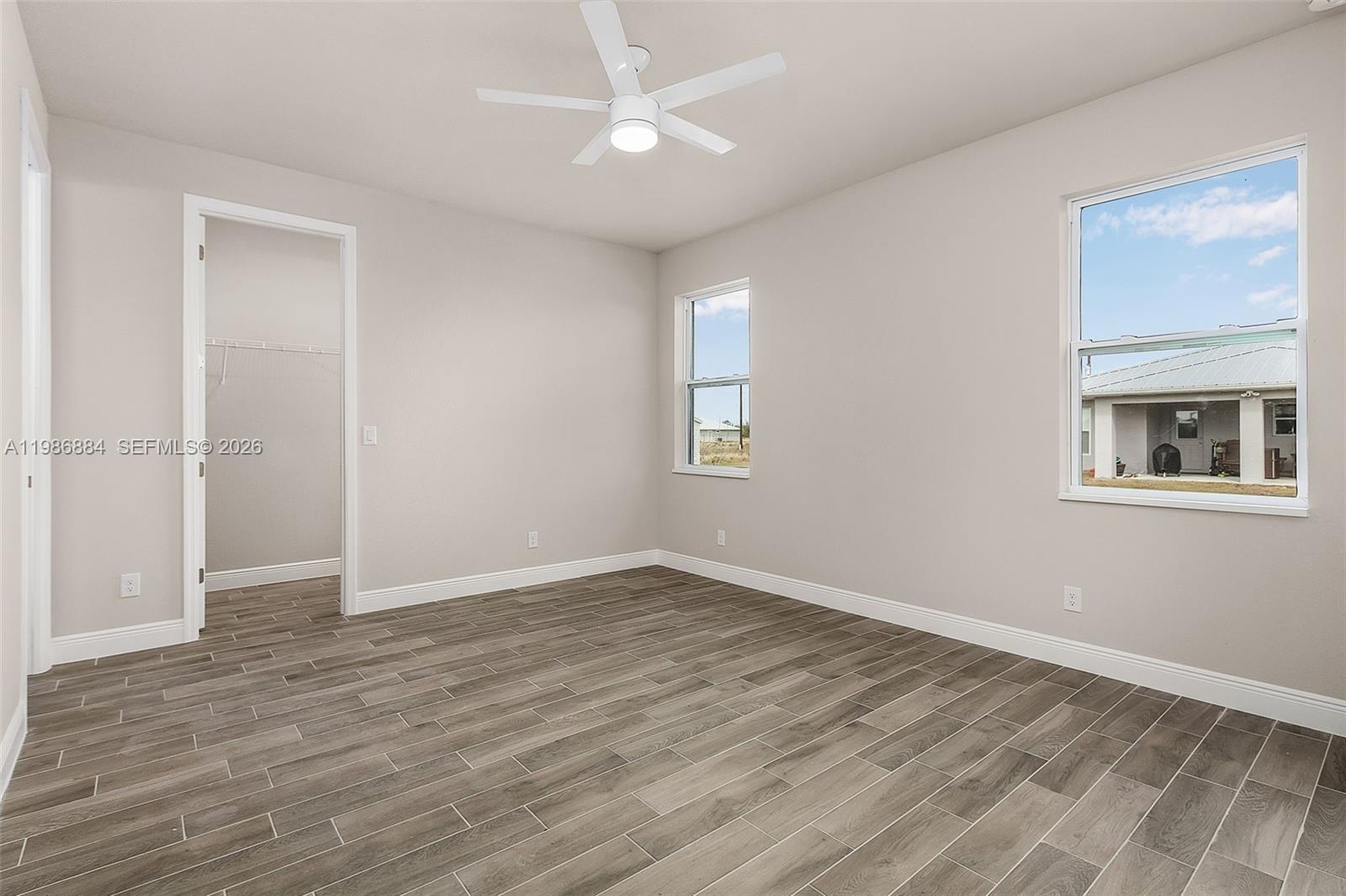 An empty bedroom features light gray walls, wood-look tile flooring, and a ceiling fan — 206 Jubilee Terr, La Belle FL 33935, LA BELLE, FL
