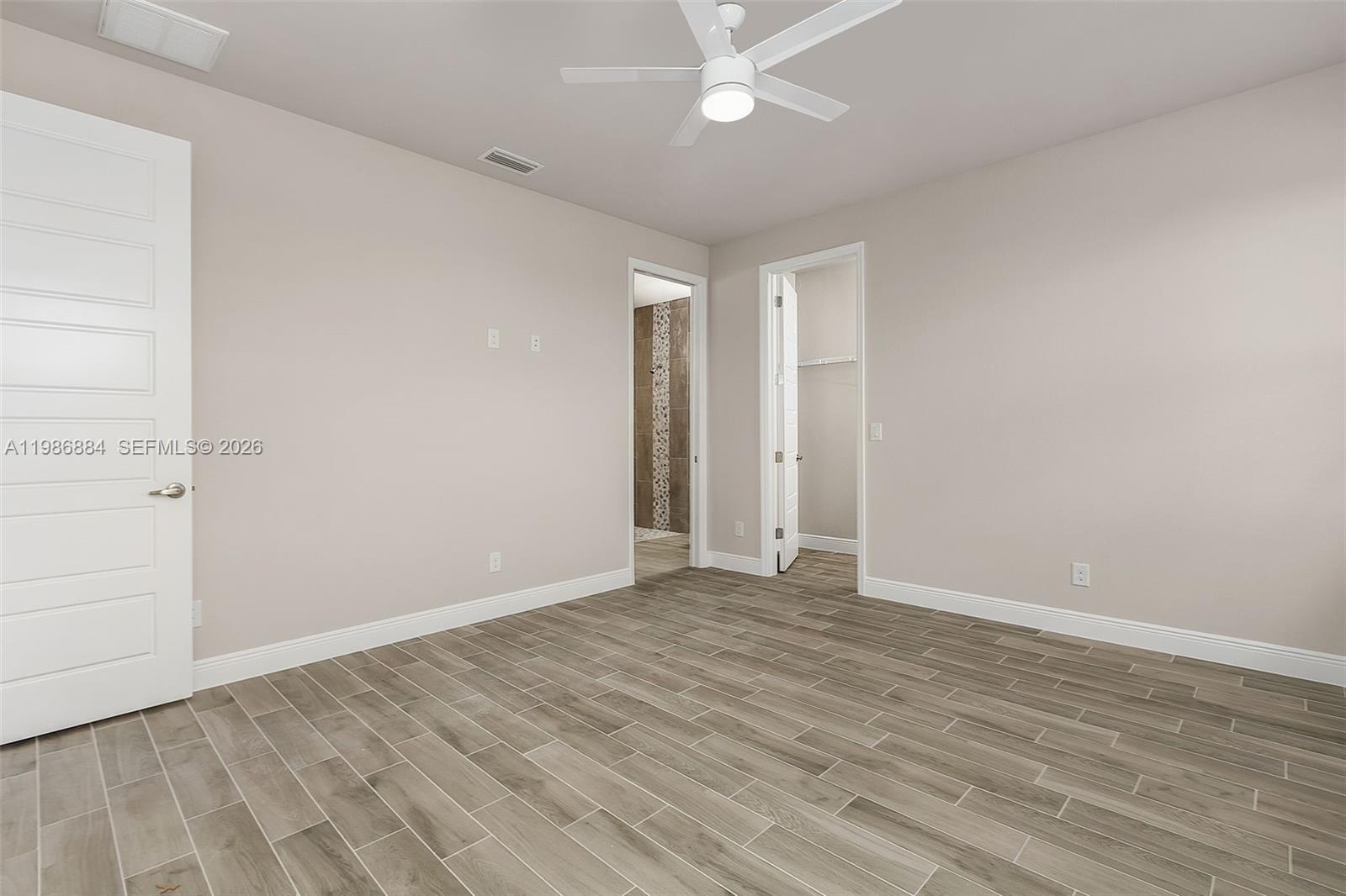 This bedroom features light-colored walls, wood-look tile flooring, a ceiling fan, and two doorways — 206 Jubilee Terr, La Belle FL 33935, LA BELLE, FL
