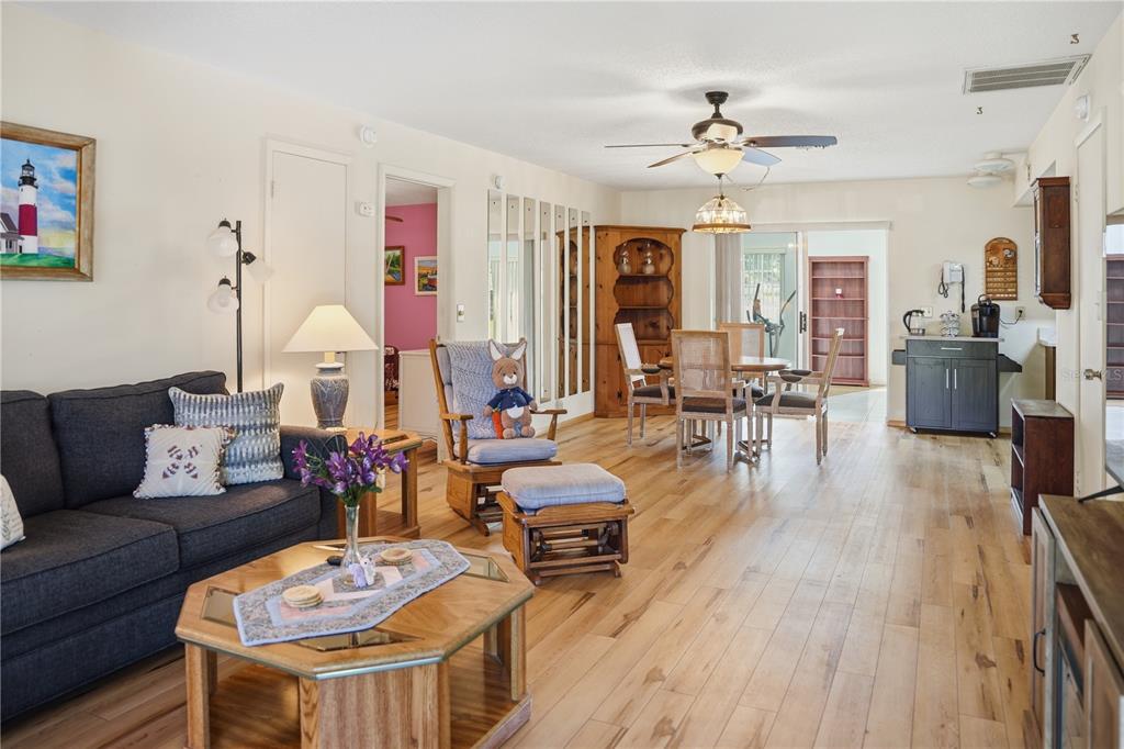 A living room and dining area feature wood flooring, a ceiling fan, and neutral walls — 103 LUCA LANE, KISSIMMEE, FL