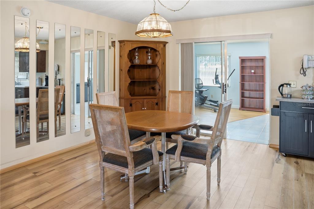 A dining area features a round wooden table, four chairs, a hutch, and mirrored wall panels — 103 LUCA LANE, KISSIMMEE, FL
