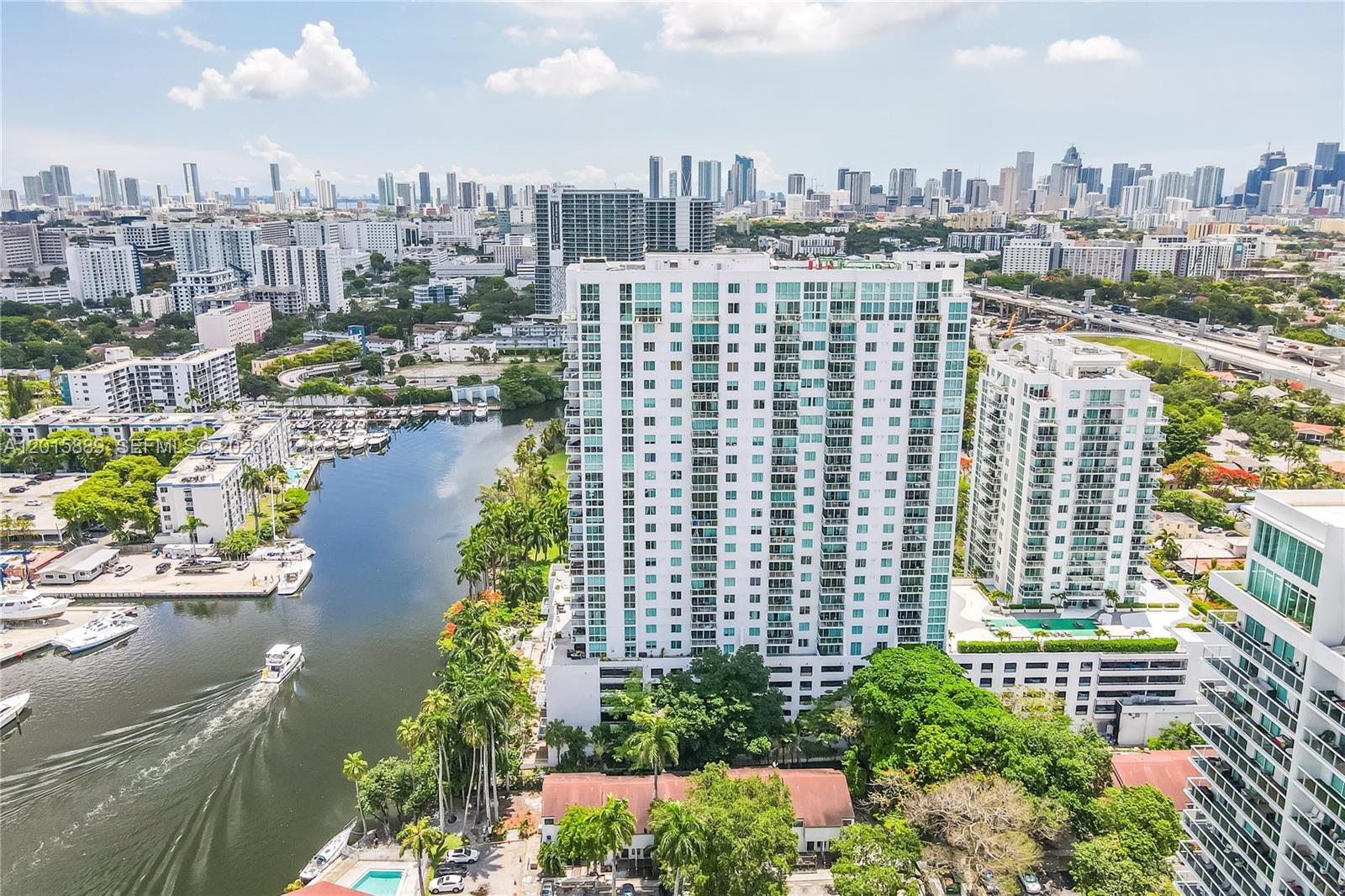 An aerial view of a tall white residential building situated next to a canal — 1861 NW S River Dr # 1003, Miami FL 33125, MIAMI, FL