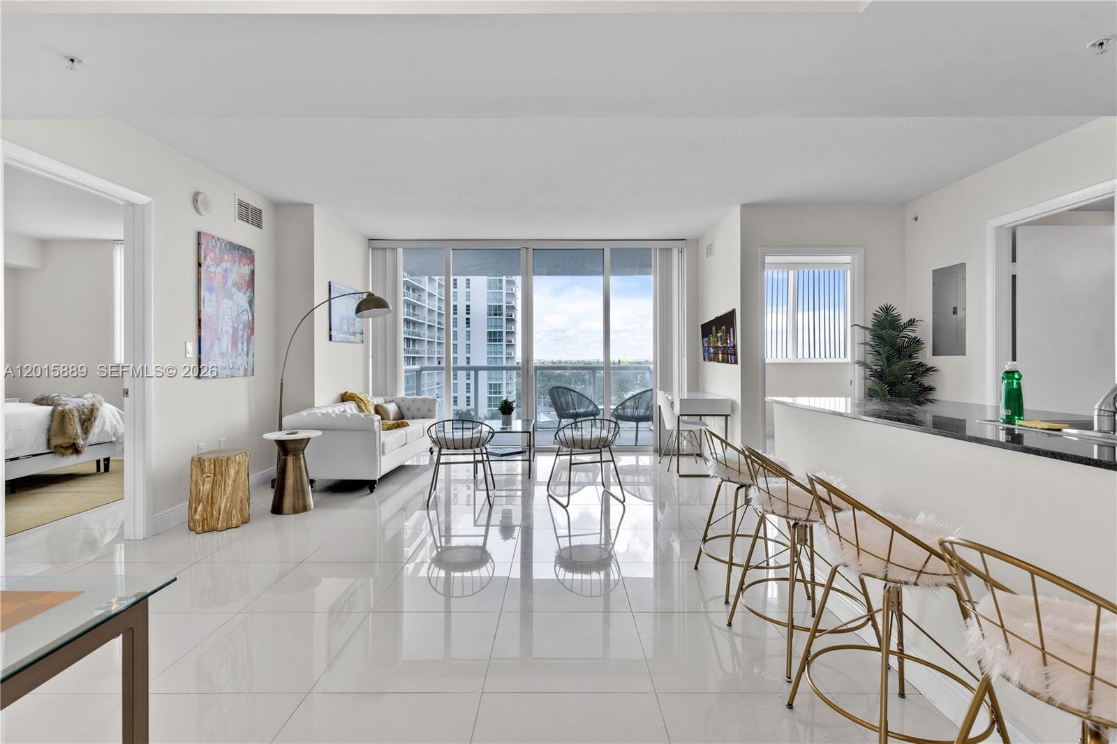 A bright, open-concept living area features white tile floors, a kitchen island, and balcony views — 1861 NW S River Dr # 1003, Miami FL 33125, MIAMI, FL
