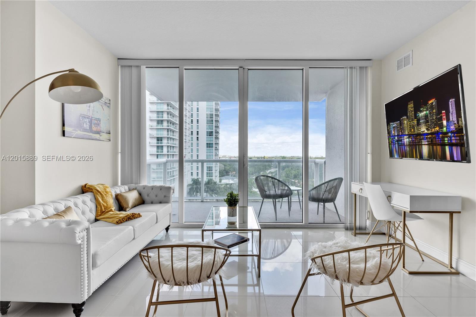 A modern living room features a white tufted sofa, glass coffee table, and balcony access — 1861 NW S River Dr # 1003, Miami FL 33125, MIAMI, FL