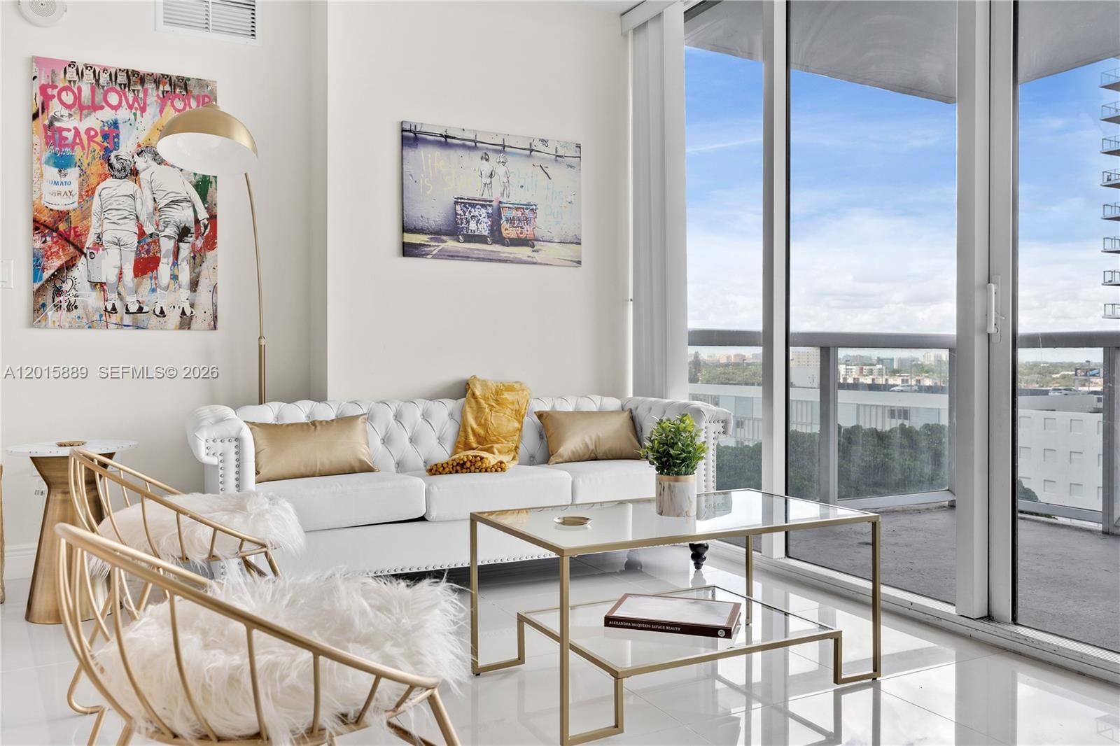 A modern living room features a white tufted sofa, glass coffee table, and floor-to-ceiling windows — 1861 NW S River Dr # 1003, Miami FL 33125, MIAMI, FL