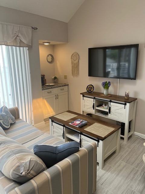 A living room features a striped sofa, a coffee table, and a wall-mounted television — 1605 S Us Highway 1, Jupiter FL 33477, JUPITER, FL