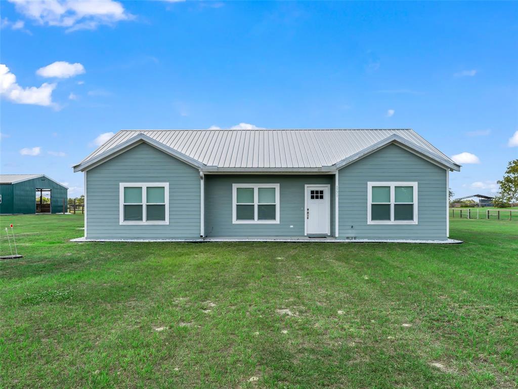A single-story house with light blue siding and a metal roof sits on grass — 1771 SE 119TH AVENUE, MORRISTON, FL