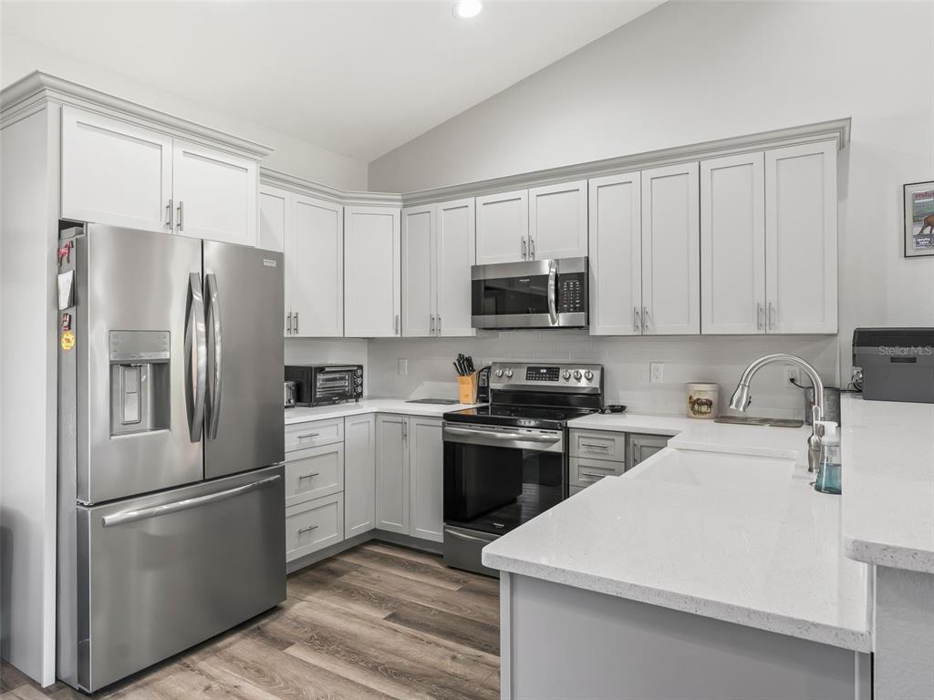 A kitchen features light gray cabinets, stainless steel appliances, and white quartz countertops — 1771 SE 119TH AVENUE, MORRISTON, FL