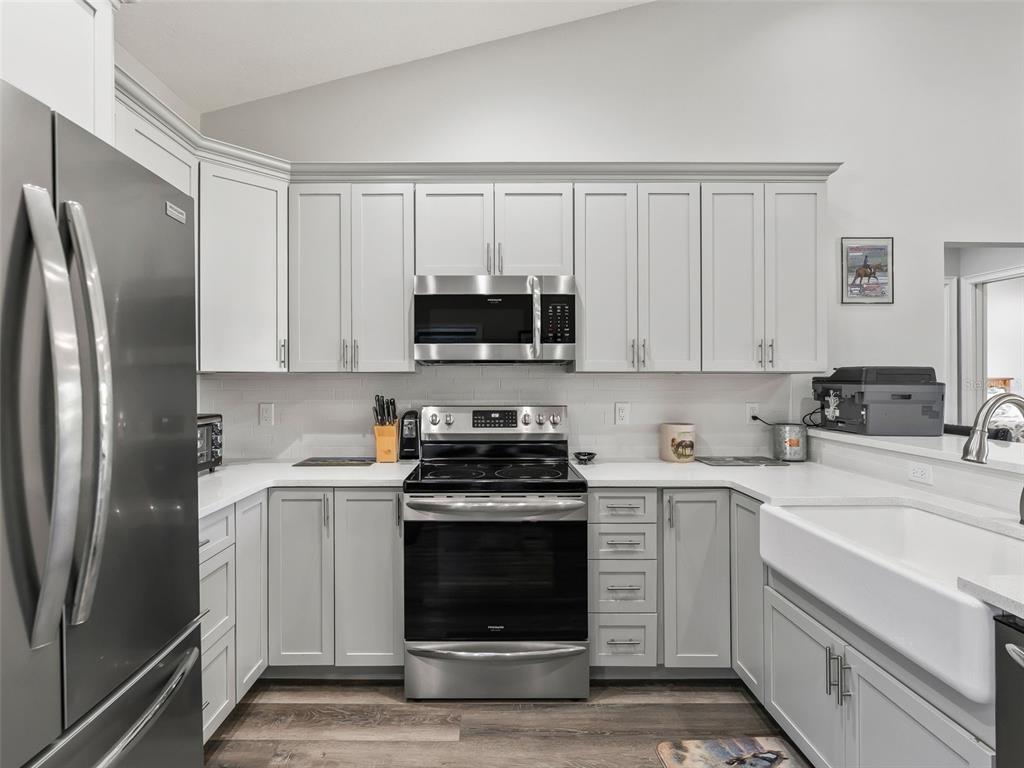 A kitchen features light gray cabinets, stainless steel appliances, white countertops, and a farmhouse sink — 1771 SE 119TH AVENUE, MORRISTON, FL