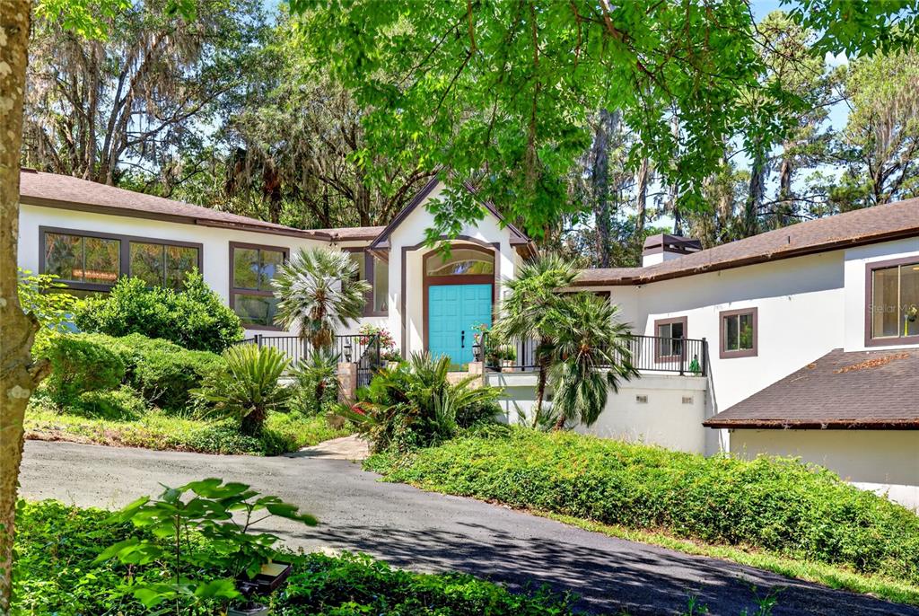 A white house with a bright blue front door sits at the end of a driveway — 17704 SE 59TH STREET, MICANOPY, FL